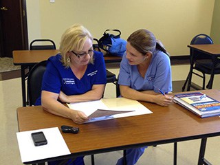 Teacher at Academy of Dental Assisting helping a student with her work